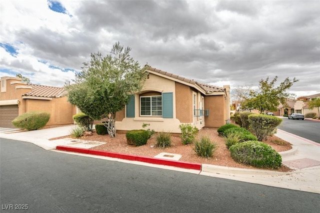 mediterranean / spanish-style house with stucco siding, a garage, concrete driveway, and a tiled roof