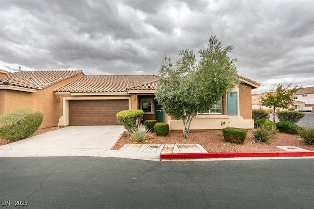 view of front of property with concrete driveway, a tiled roof, an attached garage, and stucco siding