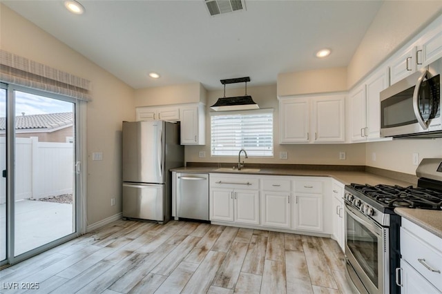 kitchen with visible vents, light wood-style flooring, a sink, appliances with stainless steel finishes, and white cabinetry