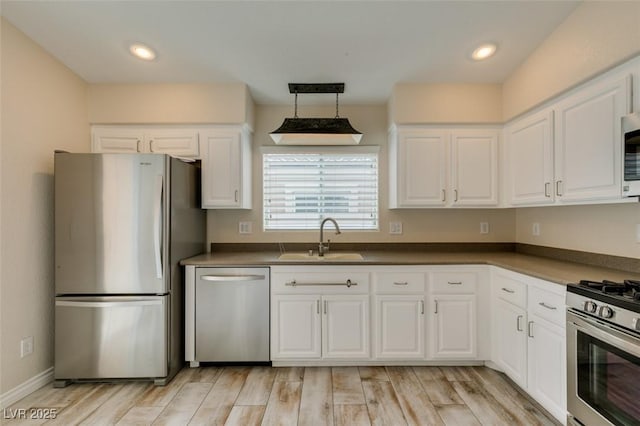 kitchen with dark countertops, light wood-type flooring, appliances with stainless steel finishes, and a sink