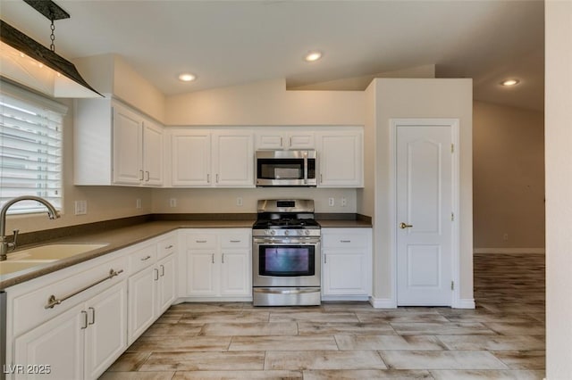 kitchen featuring white cabinetry, dark countertops, appliances with stainless steel finishes, and a sink