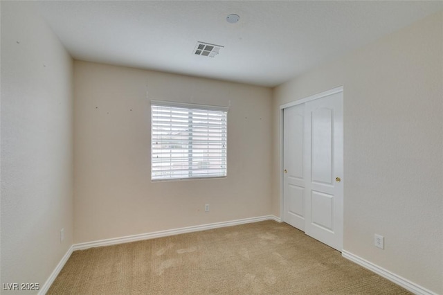 carpeted spare room featuring visible vents and baseboards