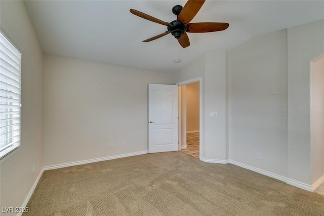 spare room with baseboards, light colored carpet, and ceiling fan