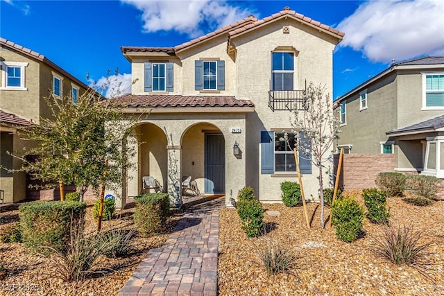 mediterranean / spanish home with stucco siding, fence, a porch, and a tile roof