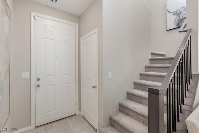 foyer entrance featuring light tile patterned floors and stairs