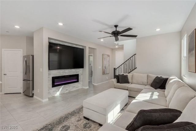 living area featuring stairway, recessed lighting, ceiling fan, and a glass covered fireplace