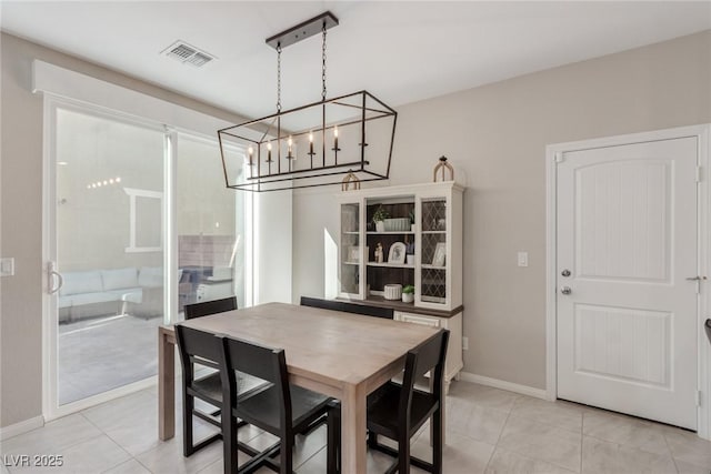 dining space with an inviting chandelier, light tile patterned flooring, baseboards, and visible vents