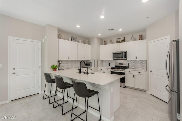 kitchen with visible vents, a sink, stainless steel appliances, a breakfast bar area, and white cabinets