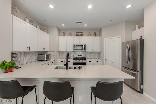 kitchen with visible vents, a breakfast bar, a peninsula, a sink, and appliances with stainless steel finishes