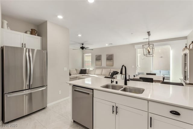 kitchen with a sink, open floor plan, stainless steel appliances, white cabinets, and light countertops