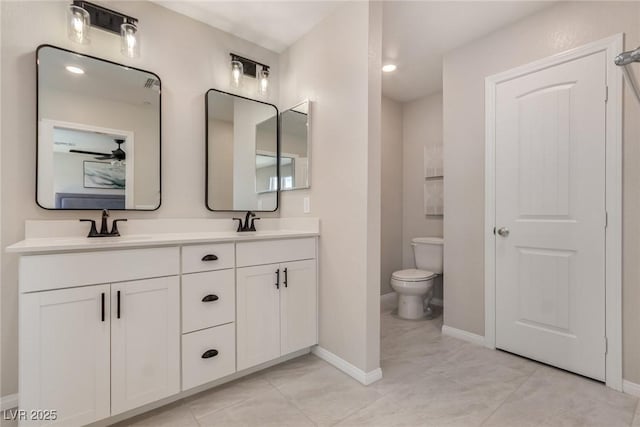 full bath with double vanity, toilet, baseboards, and a sink