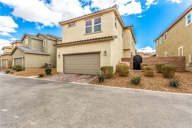 mediterranean / spanish home featuring a gate, an attached garage, stucco siding, a tile roof, and decorative driveway