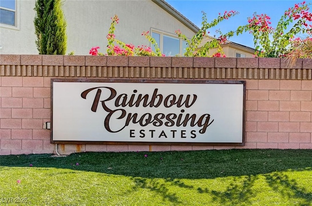 community / neighborhood sign featuring a lawn and fence