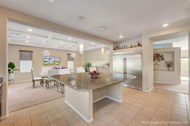 kitchen with light carpet, stainless steel built in refrigerator, coffered ceiling, a center island, and light tile patterned floors