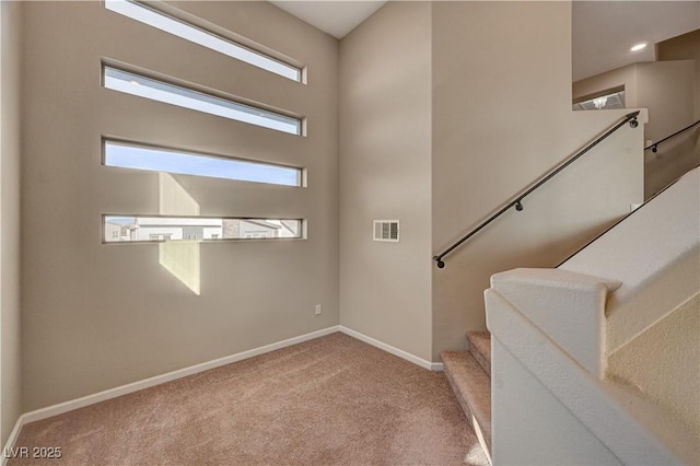 foyer entrance featuring stairs, visible vents, carpet, and baseboards