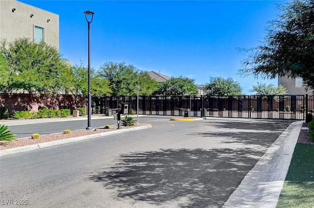 view of road with a gate, curbs, street lighting, and a gated entry