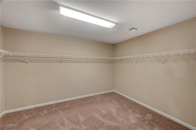 walk in closet featuring visible vents and light colored carpet