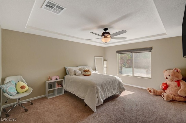 carpeted bedroom featuring a ceiling fan, a raised ceiling, baseboards, and visible vents