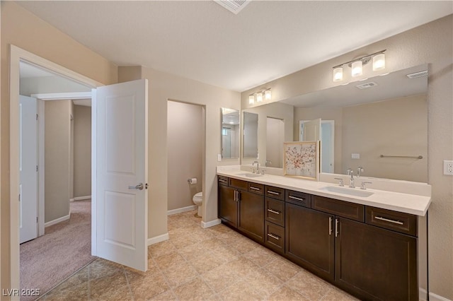 bathroom with double vanity, toilet, baseboards, and a sink