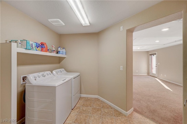 clothes washing area featuring baseboards, laundry area, a textured ceiling, light carpet, and washing machine and dryer