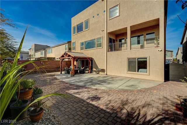 back of house featuring a gazebo, stucco siding, a patio, and fence