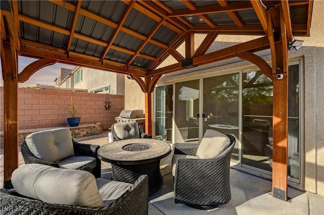 view of patio with grilling area, an outdoor living space with a fire pit, and fence