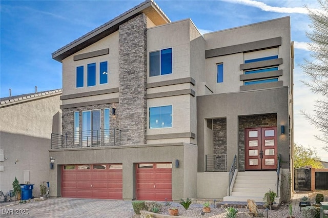 modern home featuring an attached garage, stone siding, driveway, and stucco siding