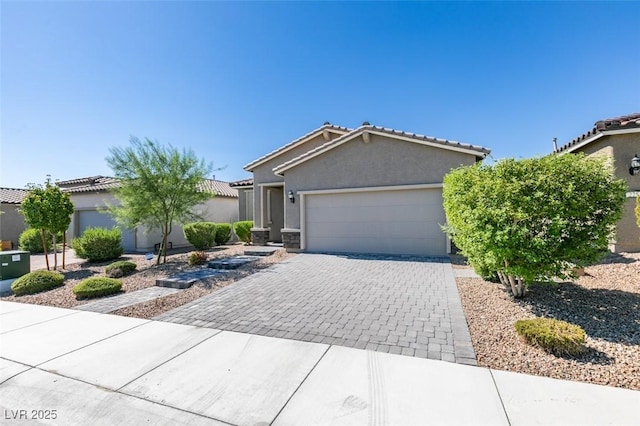 view of front of house with stucco siding, an attached garage, a tile roof, and decorative driveway