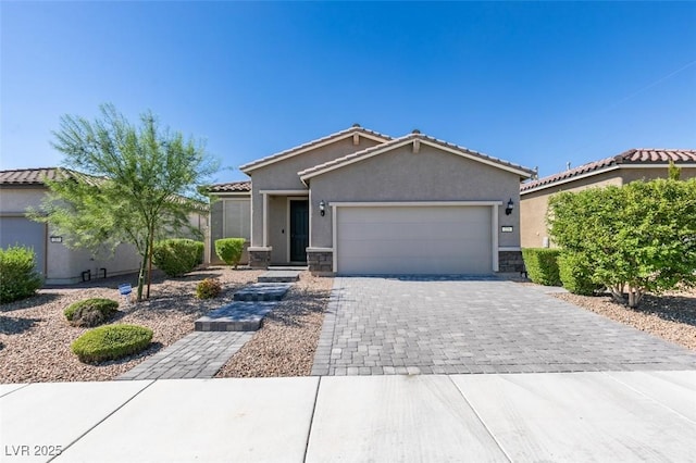 view of front of home featuring stucco siding, a garage, stone siding, a tiled roof, and decorative driveway