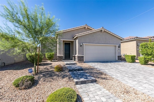 view of front of house with stucco siding, decorative driveway, stone siding, an attached garage, and a tiled roof