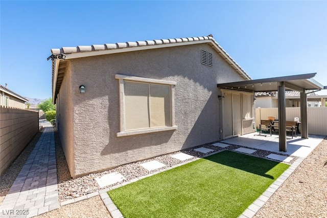 rear view of property featuring a patio, a fenced backyard, a lawn, and stucco siding