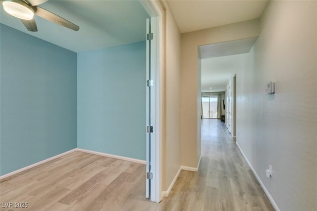 hall featuring baseboards and light wood-style flooring