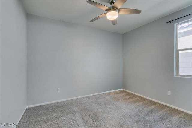 carpeted spare room featuring baseboards and a ceiling fan