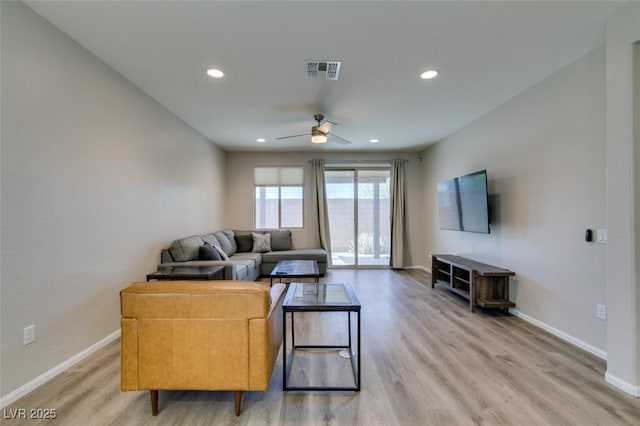 living room featuring light wood-style flooring, baseboards, visible vents, and ceiling fan