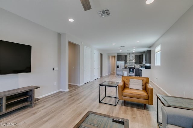 living room with light wood finished floors, visible vents, recessed lighting, and baseboards