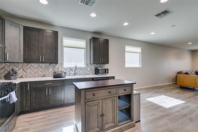 kitchen featuring range with gas stovetop, stainless steel microwave, visible vents, and a sink