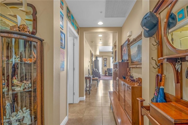 hall featuring light tile patterned flooring and baseboards