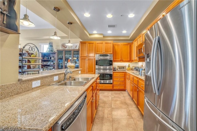 kitchen with visible vents, a tray ceiling, appliances with stainless steel finishes, hanging light fixtures, and a sink