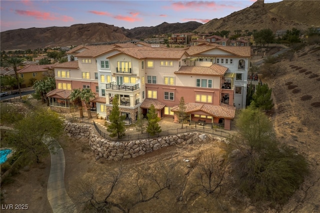 rear view of house featuring a balcony, a residential view, stucco siding, a tile roof, and a mountain view