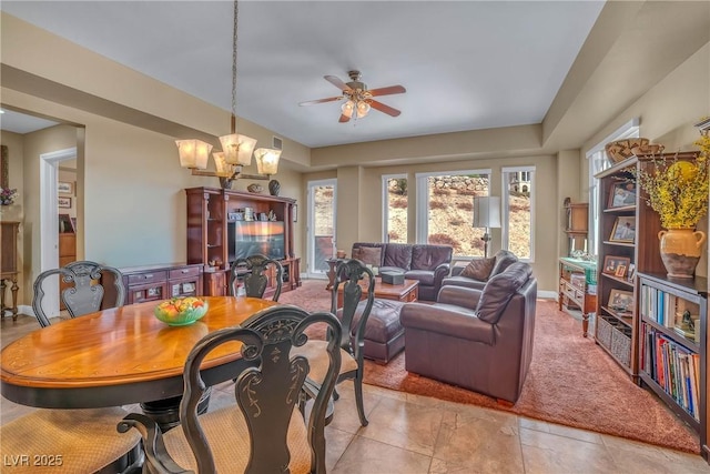 carpeted dining room featuring baseboards and ceiling fan with notable chandelier