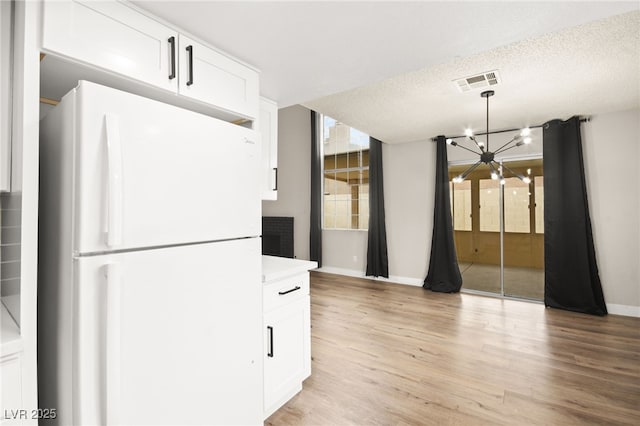 kitchen featuring visible vents, white cabinetry, an inviting chandelier, and freestanding refrigerator