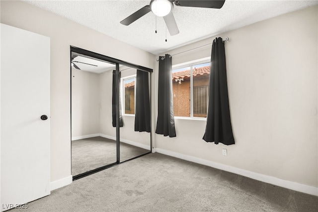 unfurnished bedroom with ceiling fan, baseboards, carpet floors, a closet, and a textured ceiling