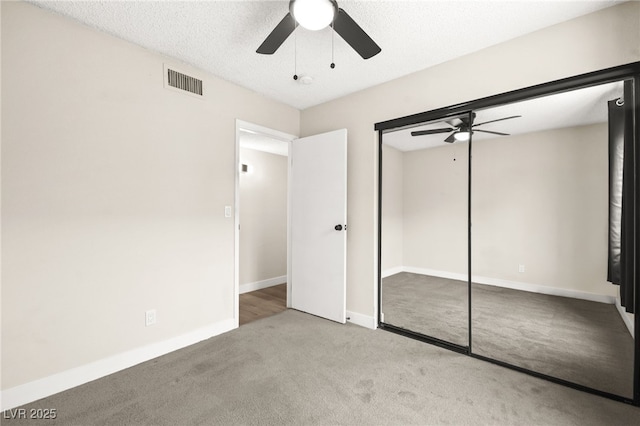 unfurnished bedroom with baseboards, visible vents, ceiling fan, a closet, and carpet flooring