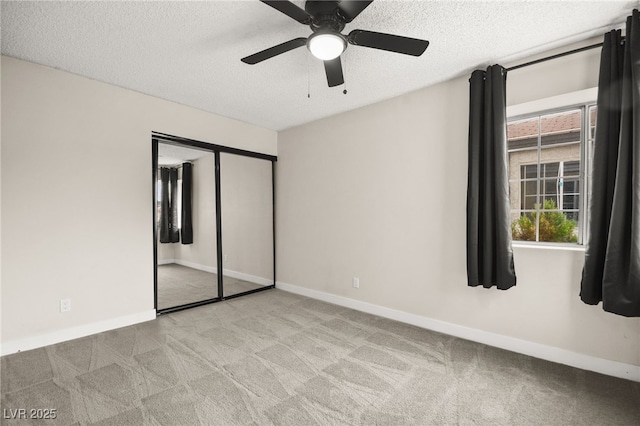 unfurnished bedroom featuring ceiling fan, a textured ceiling, baseboards, and carpet floors