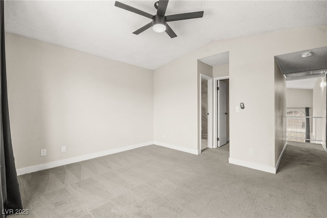 spare room with a ceiling fan, baseboards, carpet floors, vaulted ceiling, and a textured ceiling