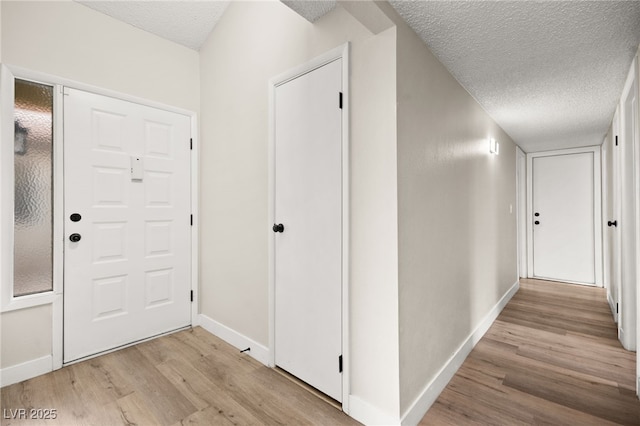 corridor featuring baseboards, a textured ceiling, and wood finished floors