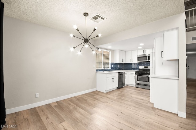 kitchen with visible vents, light countertops, decorative backsplash, appliances with stainless steel finishes, and an inviting chandelier