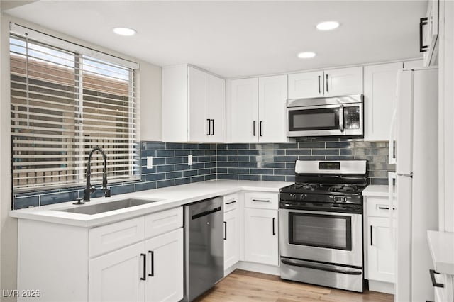 kitchen featuring a sink, stainless steel appliances, backsplash, and light countertops