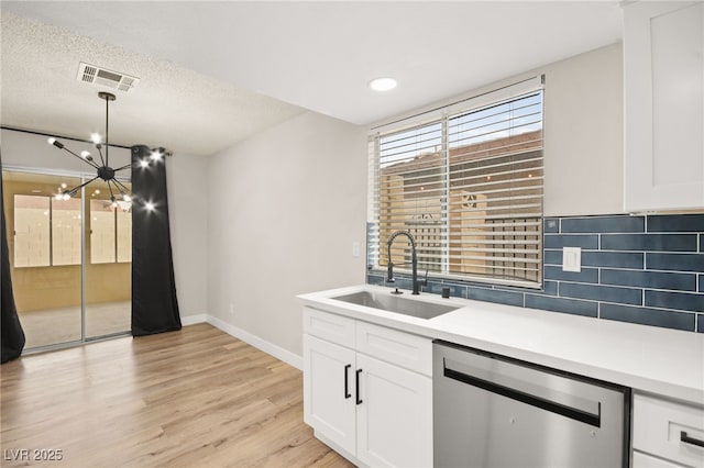 kitchen featuring tasteful backsplash, visible vents, stainless steel dishwasher, light wood-style floors, and a sink