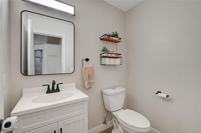 bathroom featuring toilet, vanity, and baseboards